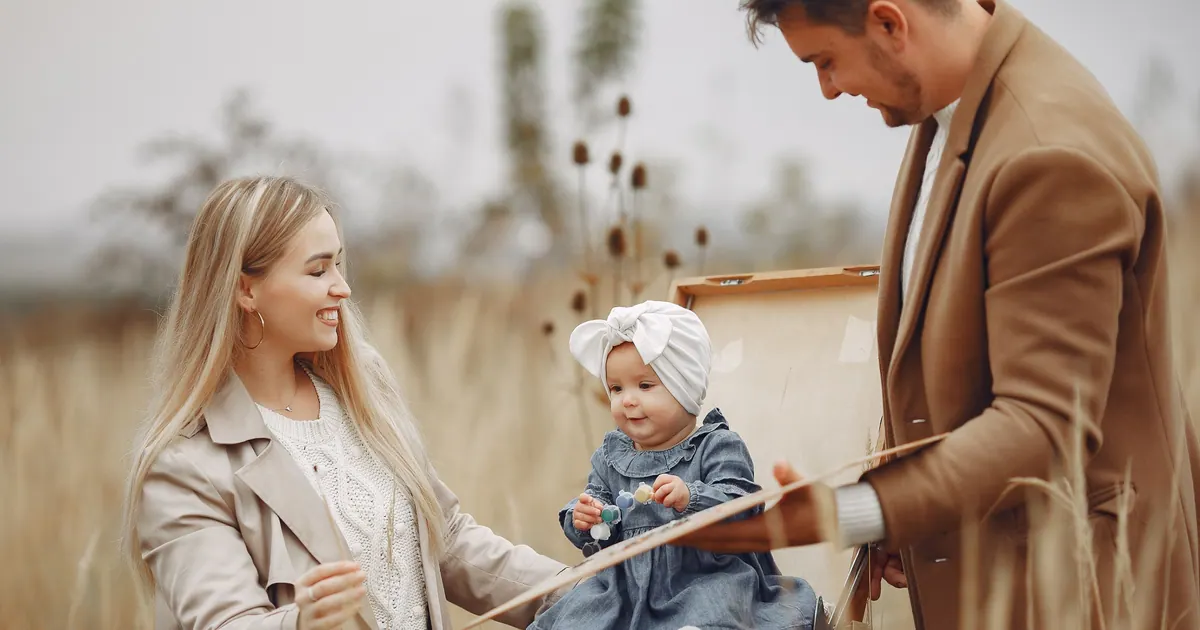 Two parents sitting with their baby in an autumn field