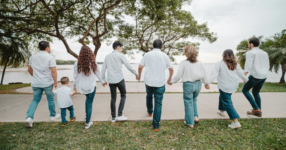 An extended family standing together beside open water